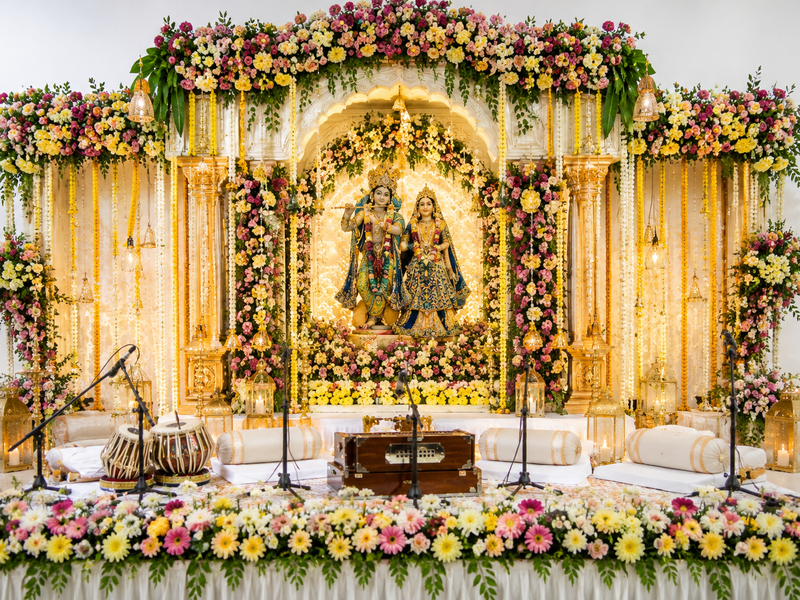 Luxury Radha Krishna floral kirtan stage with warm decorative lights